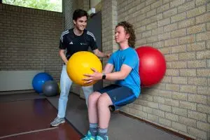 Kinderfysiotherapeut begeleidt jongere tijdens sportfysiotherapie sessie