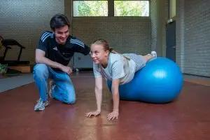 Kinderfysiotherapeut helpt tiener tijdens kidsgym in Voorschoten