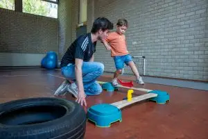 Kinderfysiotherapeut helpt peuter tijdens balans parcours